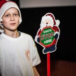 Mikołajki 2017, chłopiec, tabliczka z napisem "Santa stop here"