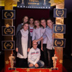 grupa młodych osób pozuje do zdjęcia, przed nimi złota rama z napisem "Cinema Festival"