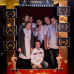 grupa młodych osób pozuje do zdjęcia, przed nimi złota rama z napisem "Cinema Festival"