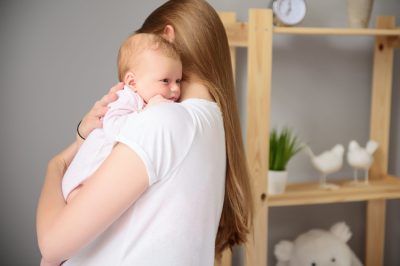 So tender embrace. Mother hugging her little cute child and holding her in arms, standing in bedroom